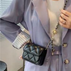 Crossbody black quilted purse with chain and leather strap.
